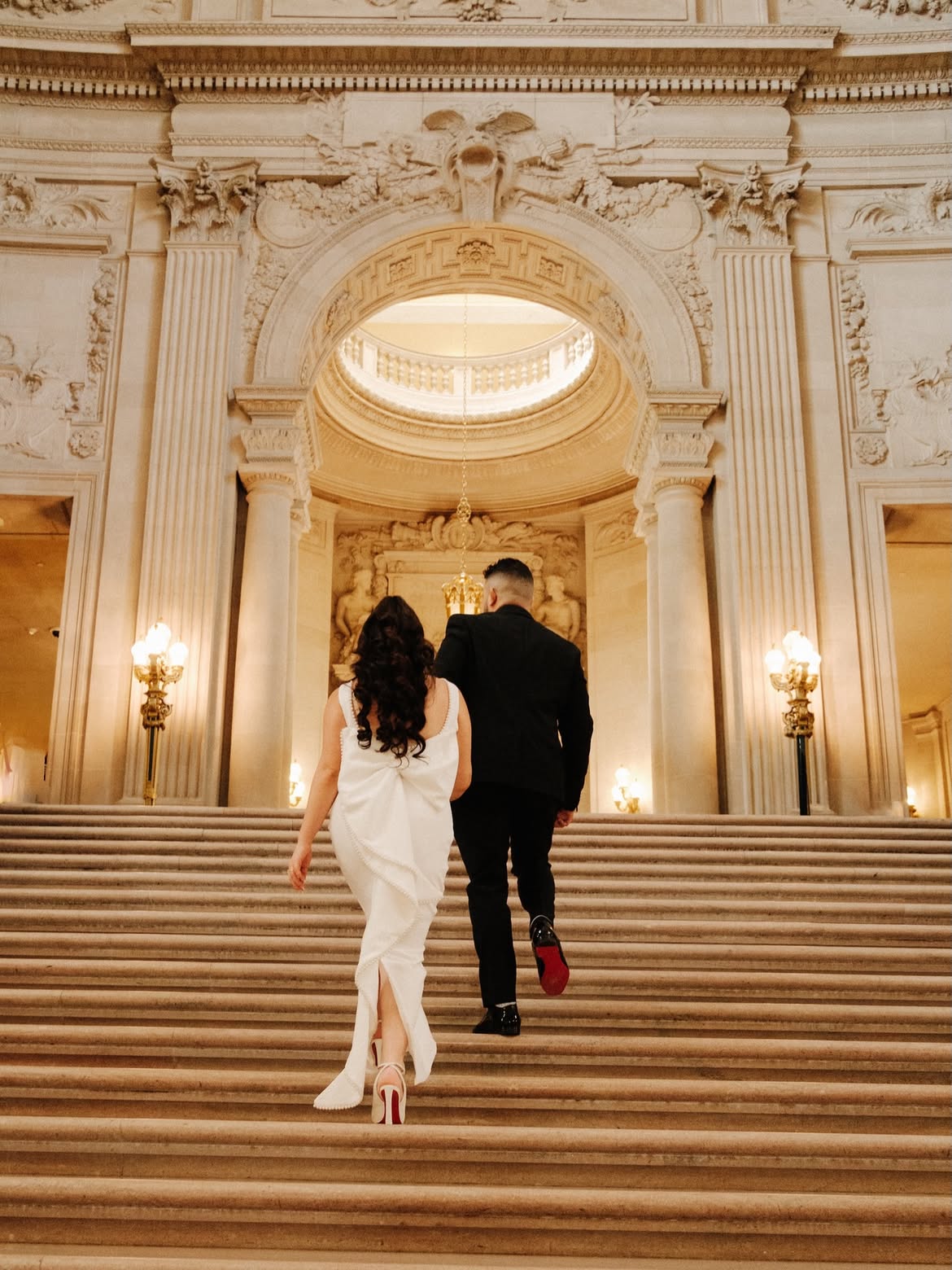 Renita and Jason walking up the City Hall stairs — couples photography by Steven Lelham in San Francisco City Hall